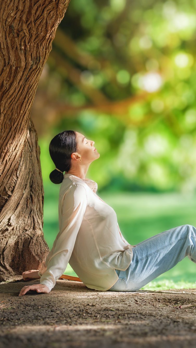 woman relaxing under big tree